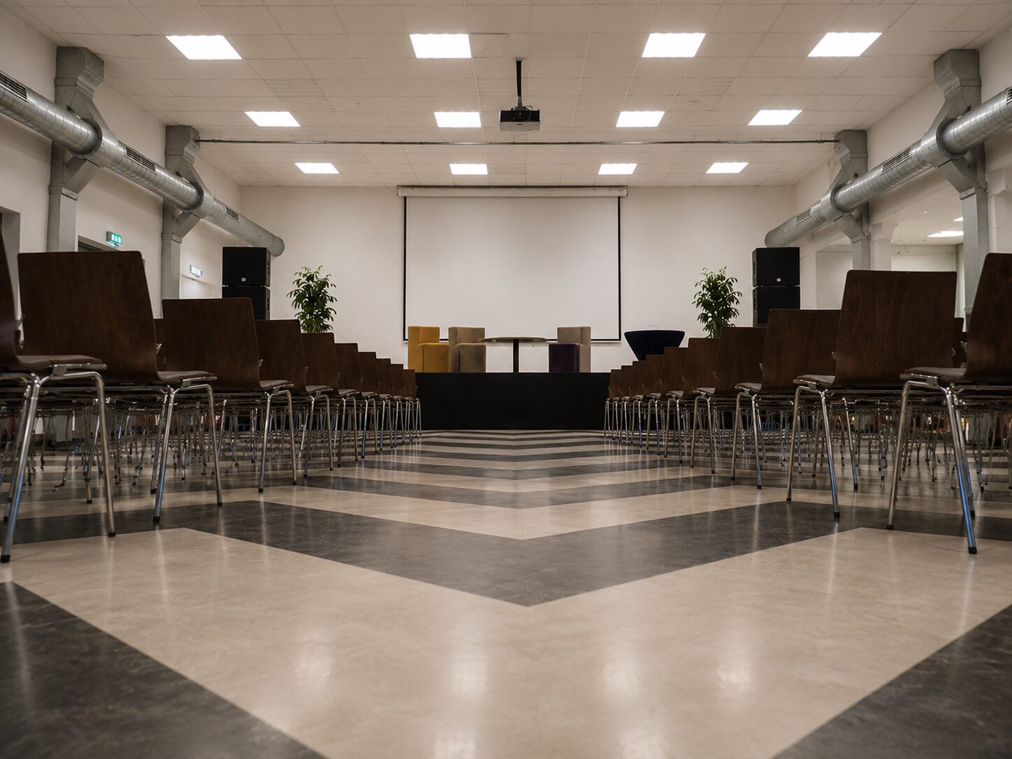 Sfeerbeeld van een lichte zaal met stoelen en projectiescherm