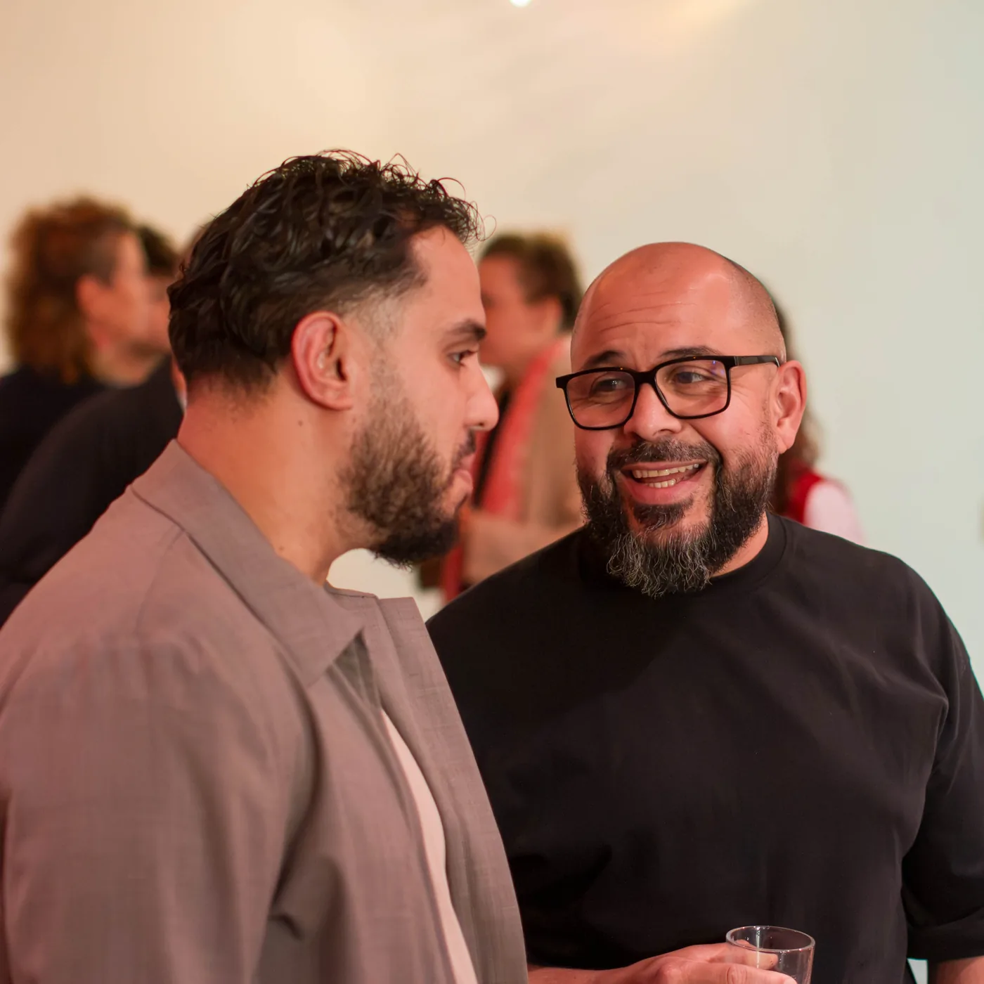 Twee mannen in gesprek na afloop van de bijeenkomst; een van hen lacht.